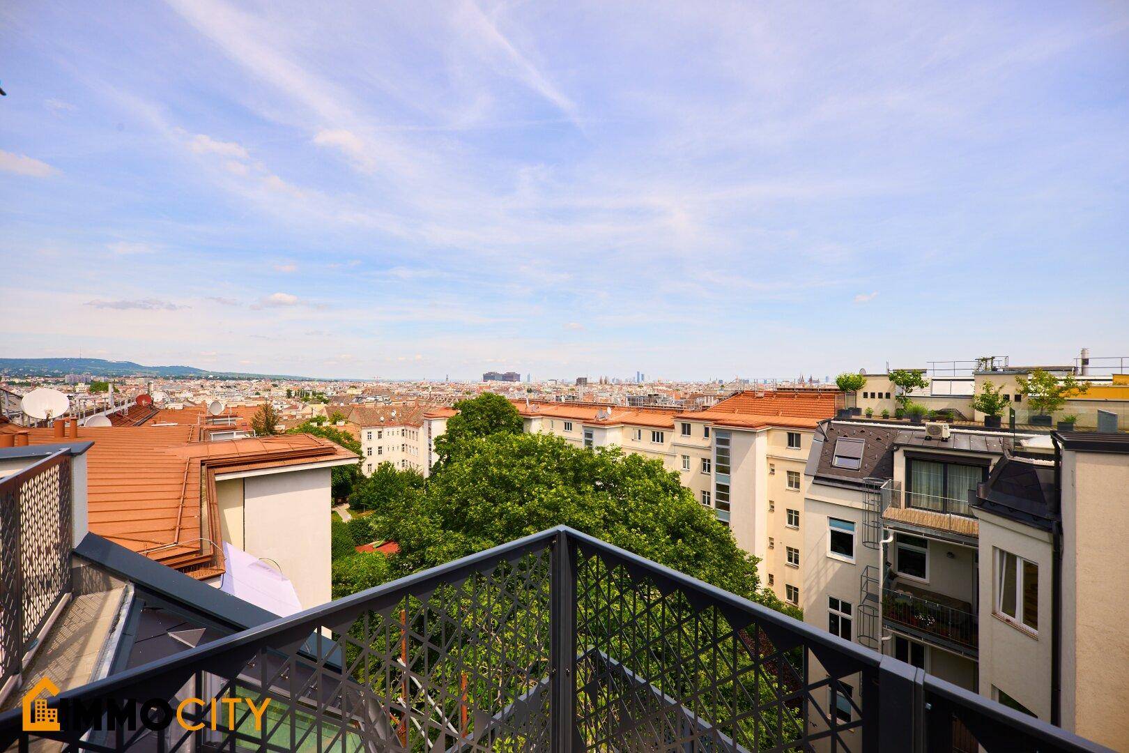 Weitläufiger Blick über die Stadt und die umliegenden Dächer von einem Balkon aus.