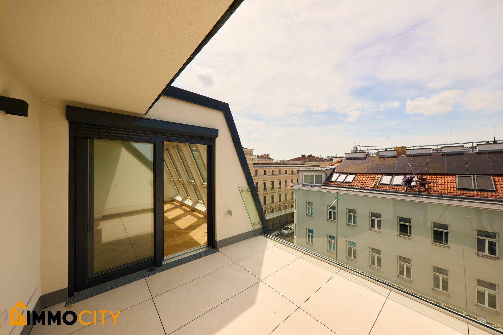 Geräumiger Balkon mit Fliesenboden und Schiebetür, bietet weite Aussicht über die Stadt.