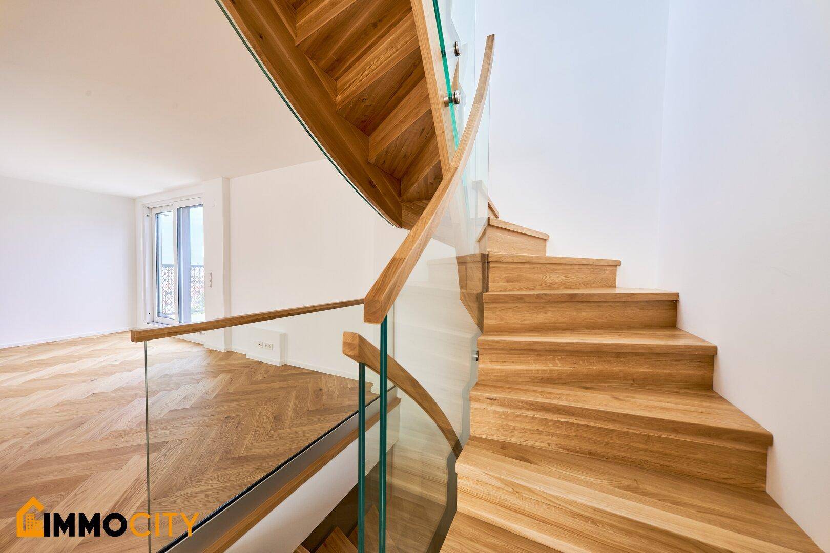 Elegante Holztreppe mit Glasgeländer, die verschiedene Ebenen des Hauses verbindet.