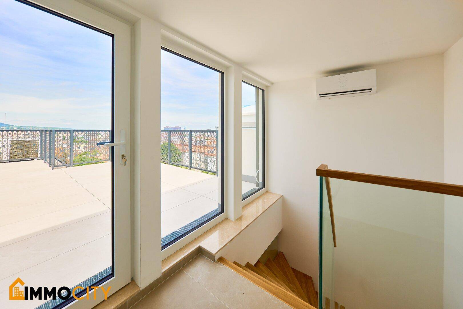 Heller Treppenaufgang mit Klimaanlage und Zugang zu einer großen Dachterrasse.