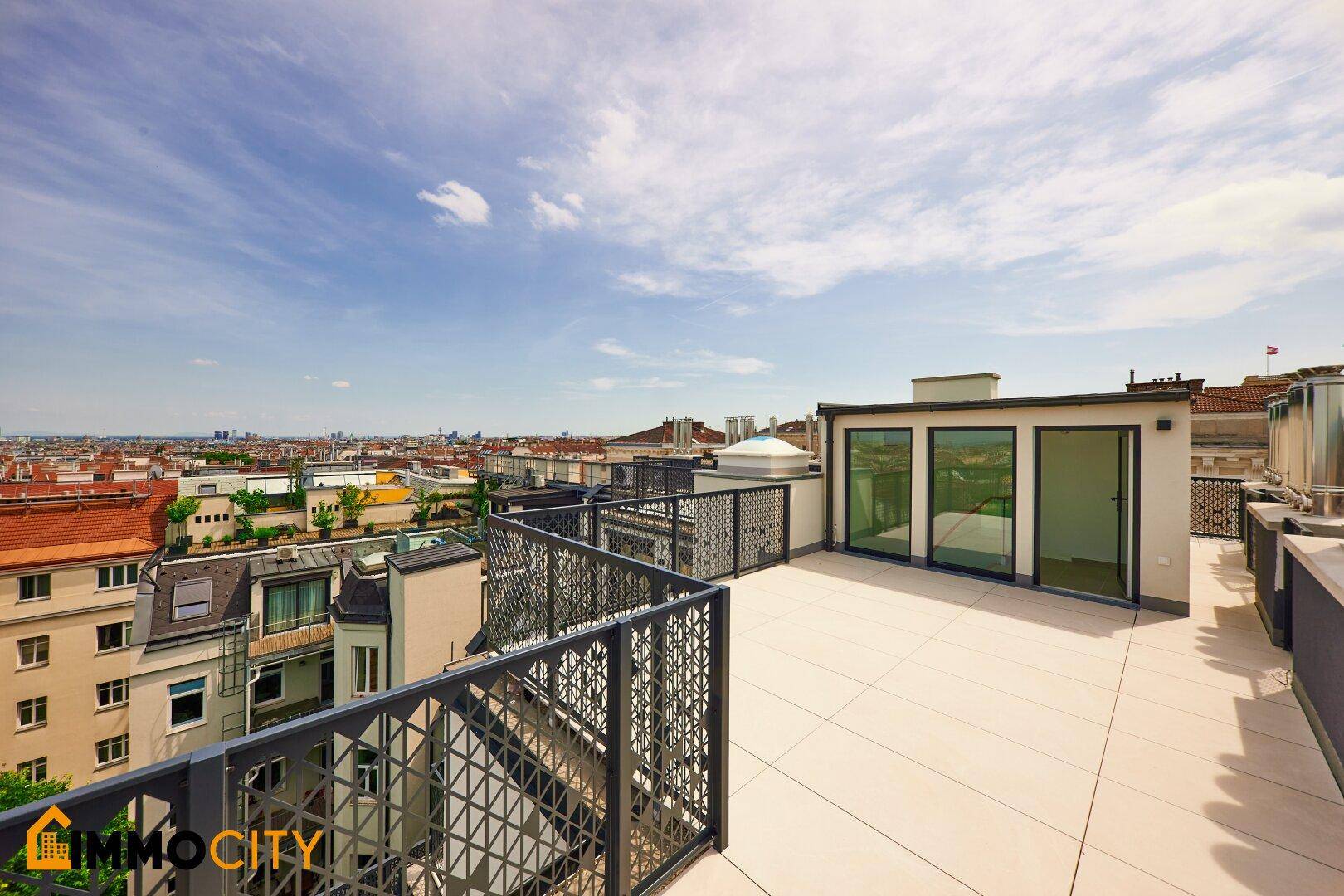 Geräumige Dachterrasse mit einem kleinen Aufbau und weitem Blick über die Stadt.