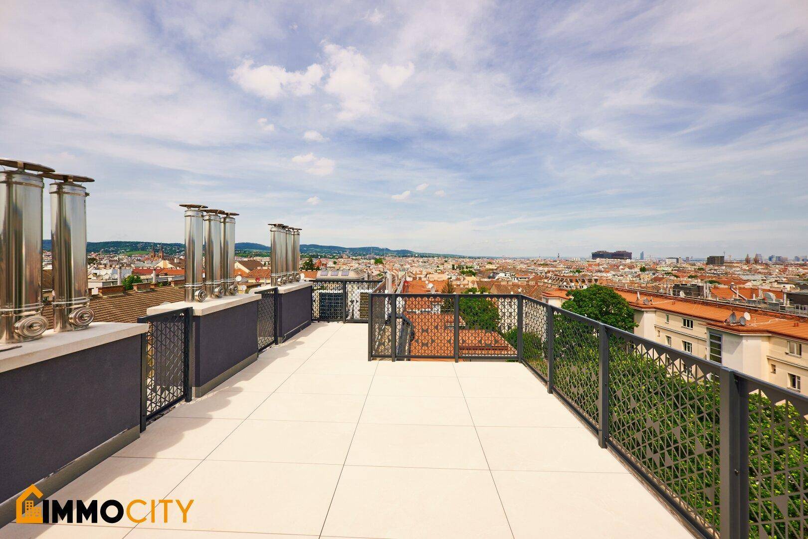 Weitläufige Dachterrasse mit mehreren Schornsteinen und Panoramablick über die Stadt.