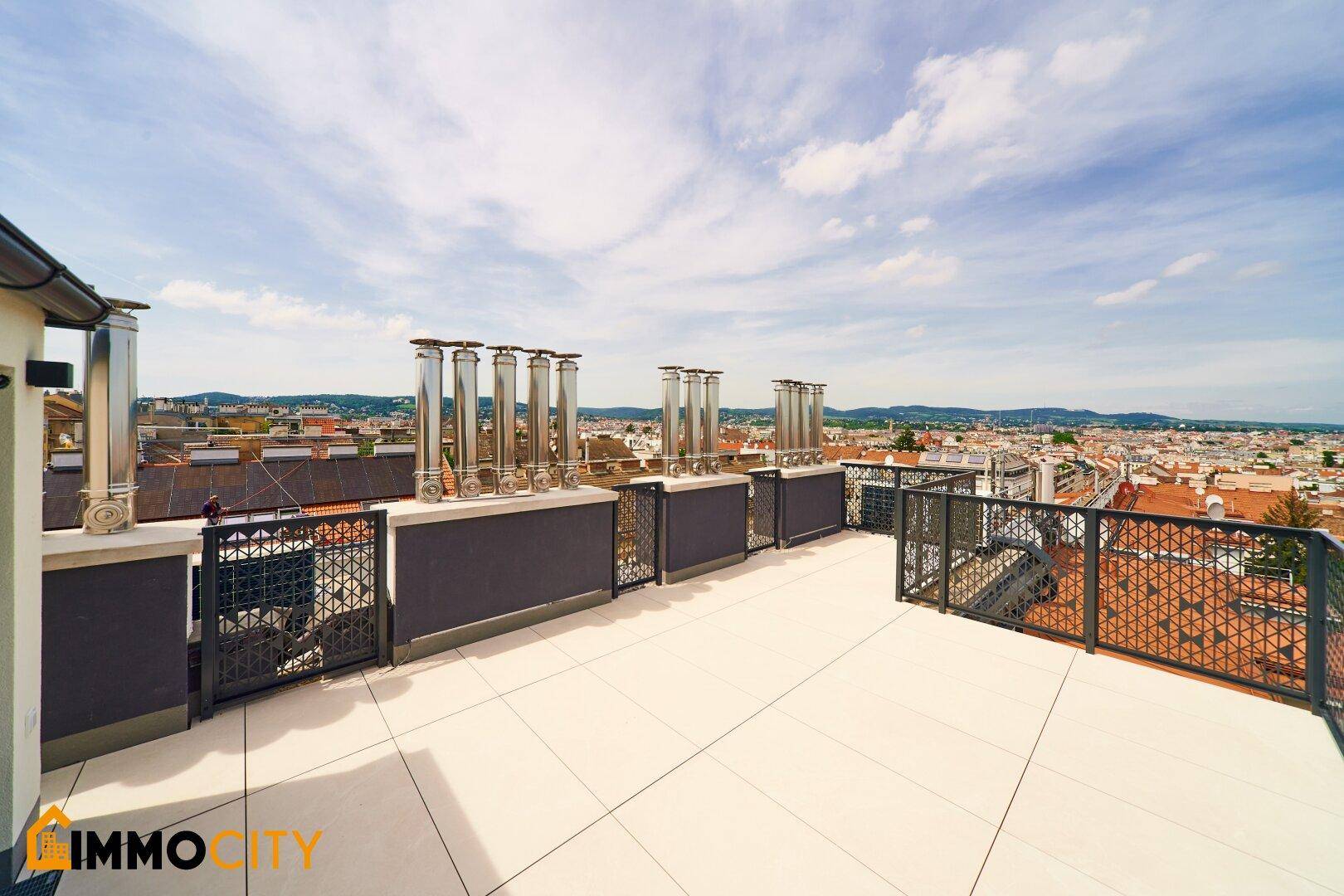 Große Dachterrasse mit modernen Schornsteinen und weitem Blick über die Stadtlandschaft.