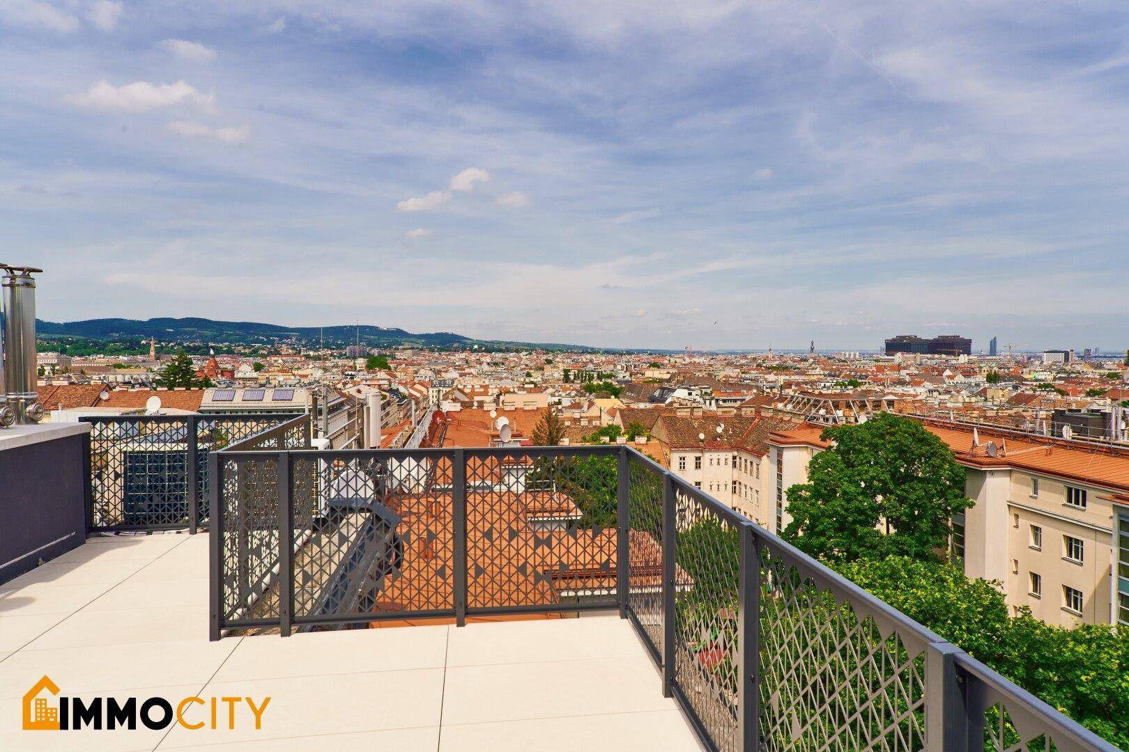 Dachterrasse mit modernem Geländer und weitem Blick über die Dächer der Stadt.