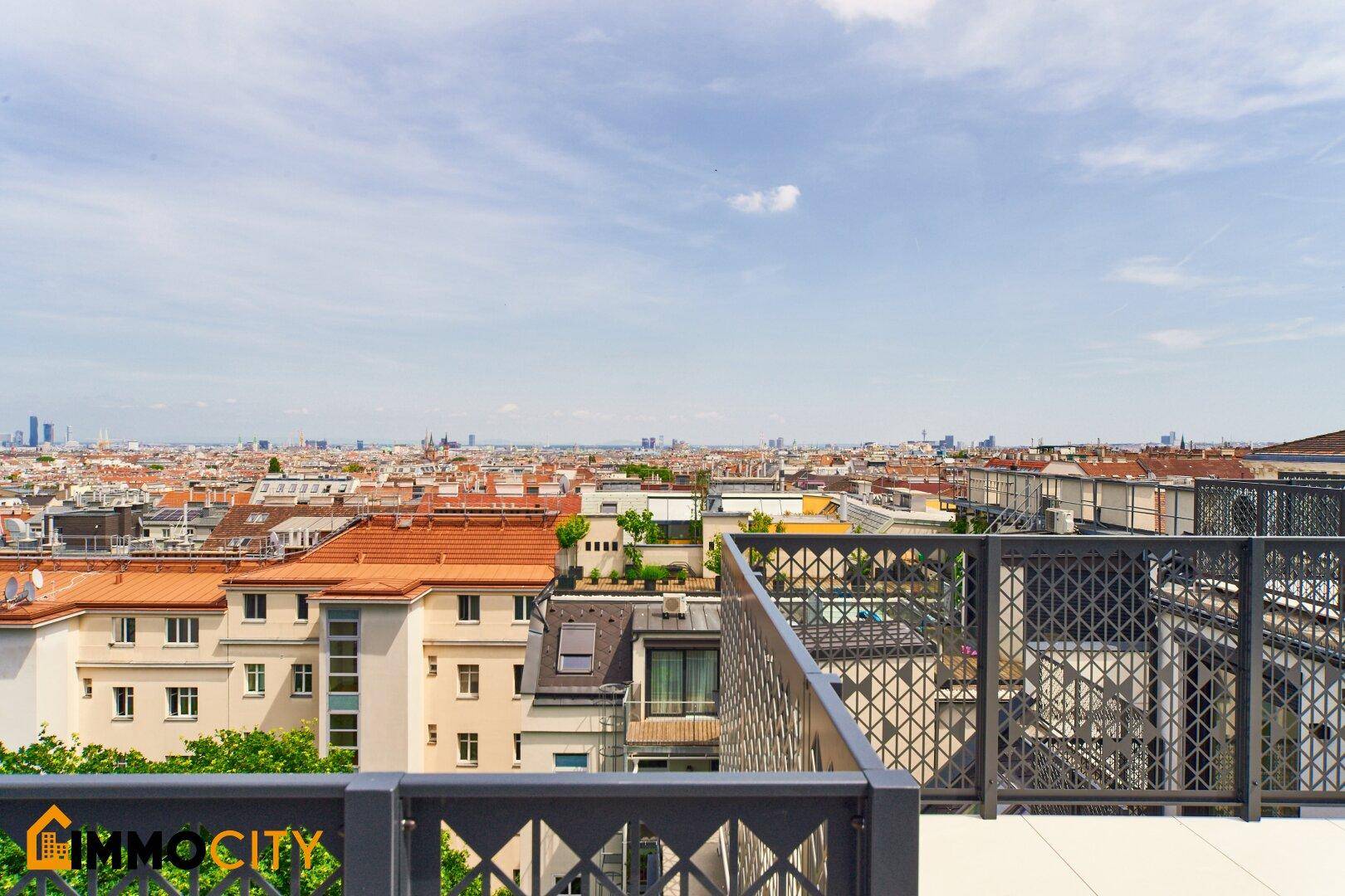 Dachterrasse mit modernem Geländer und weitem Blick über die Stadt und den Horizont.