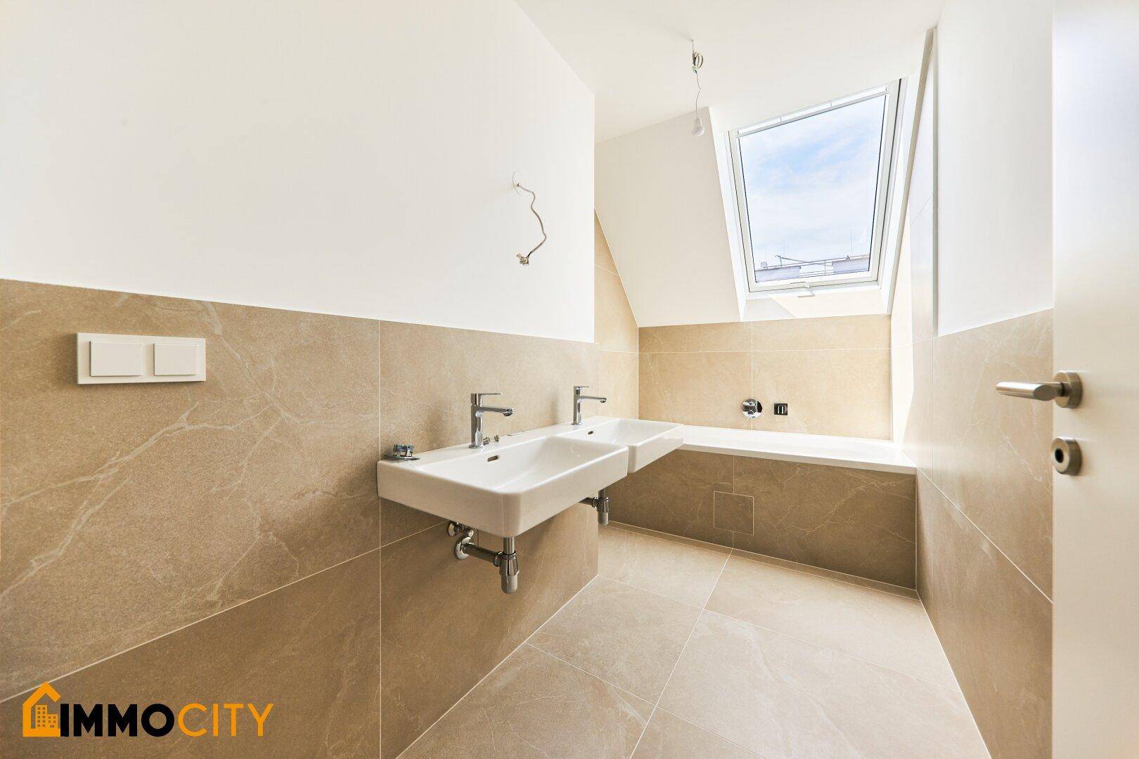 Modernes Badezimmer mit Doppelwaschbecken, Badewanne und Dachfenster für Tageslicht.