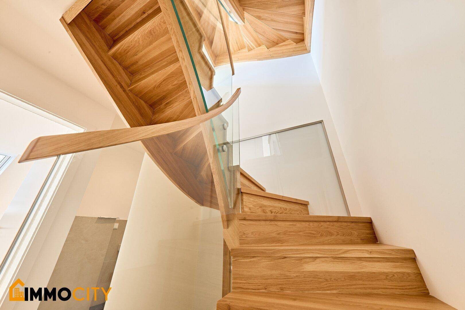 Elegante Holztreppe mit moderner Glasbrüstung, die die verschiedenen Ebenen verbindet.