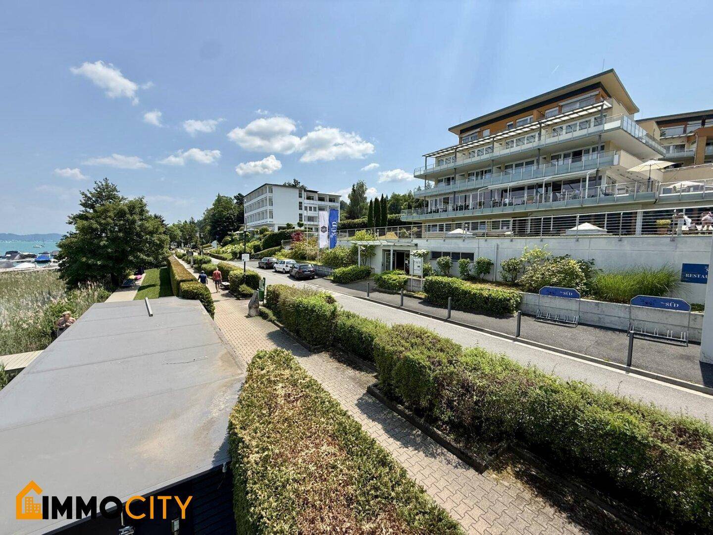 Seeseitige Ansicht eines modernen Gebäudekomplexes entlang einer gepflegten Uferpromenade.