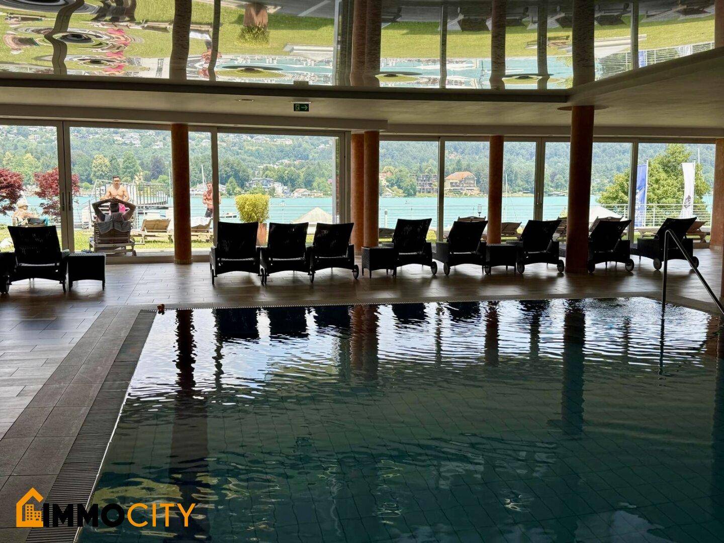 Innenpool mit klarem Wasser und Liegestühlen, die einen direkten Blick auf den See bieten.