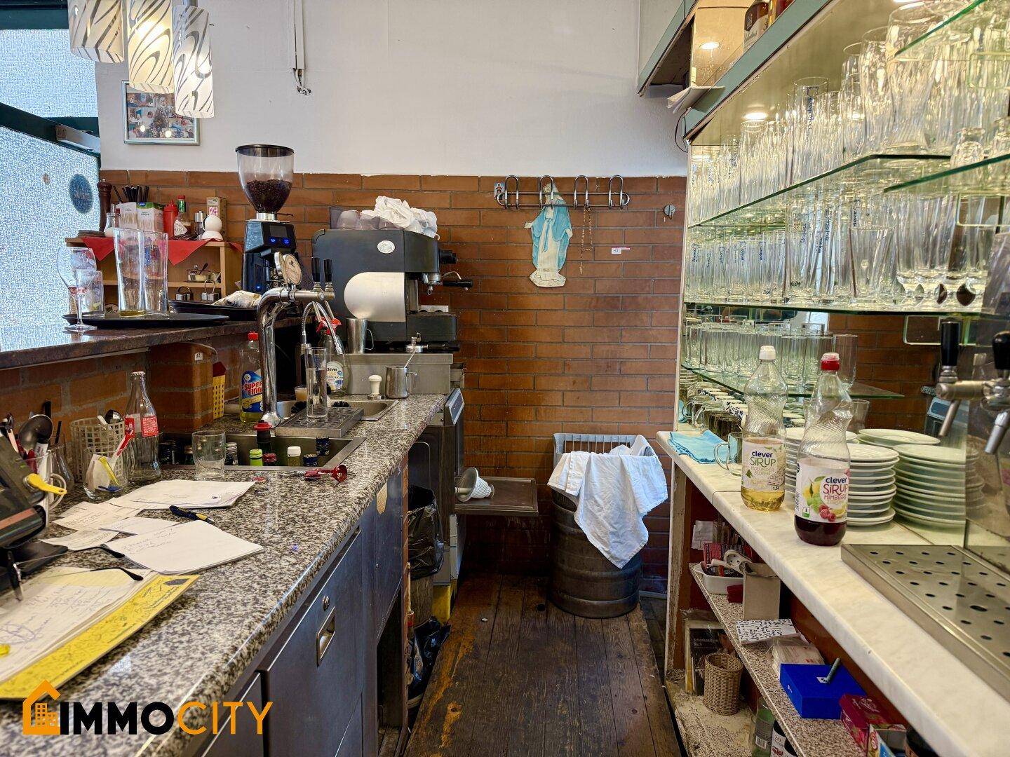 Bar-Bereich des Restaurants mit Kaffeemaschine, vielen Gläsern und einer Ziegelwand als Hintergrund.