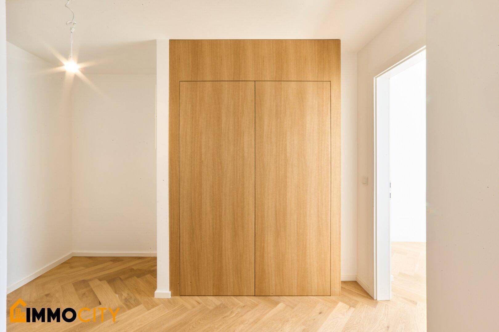 Geräumiger Bereich mit integrierten Holzschränken und elegantem Fischgrätparkettboden.