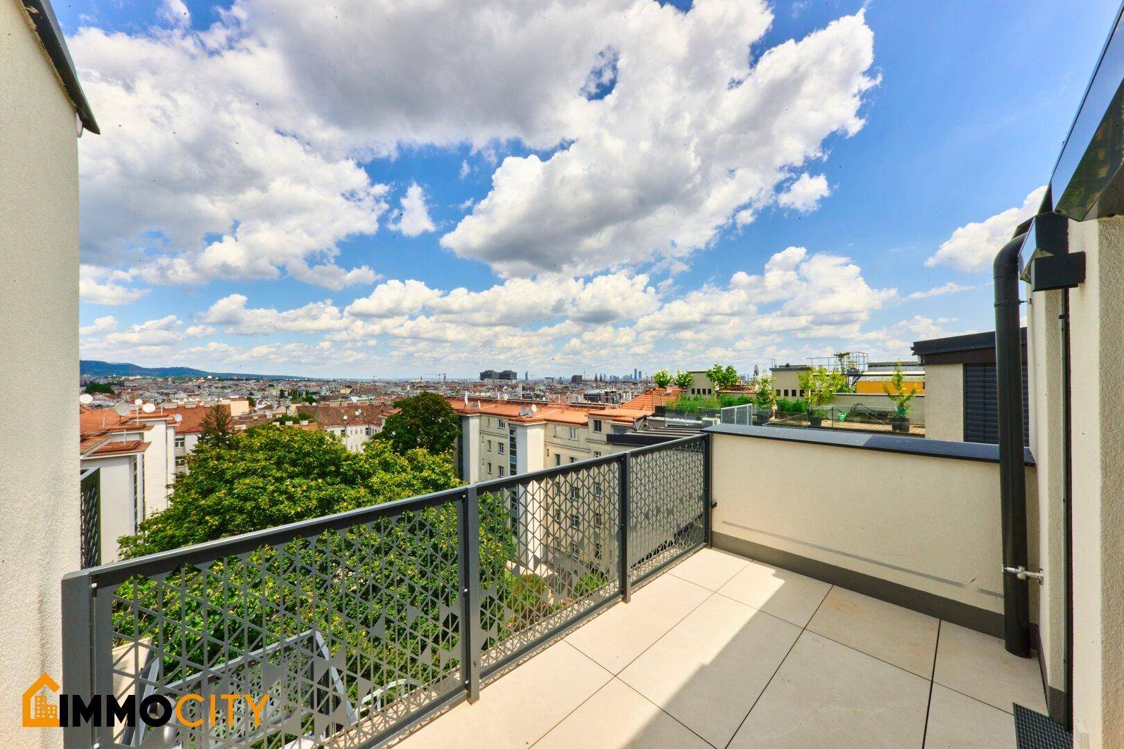 Heller Balkon mit Fliesenboden und weitem Blick über die Stadt und die umliegende Landschaft.
