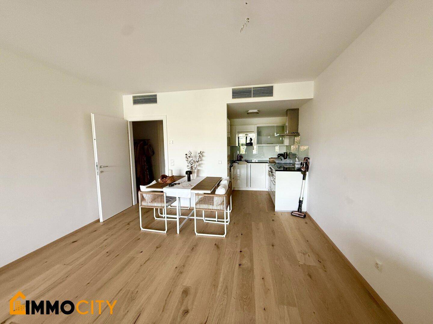Offener Essbereich mit Holzboden und integrierter moderner Küche im Hintergrund.