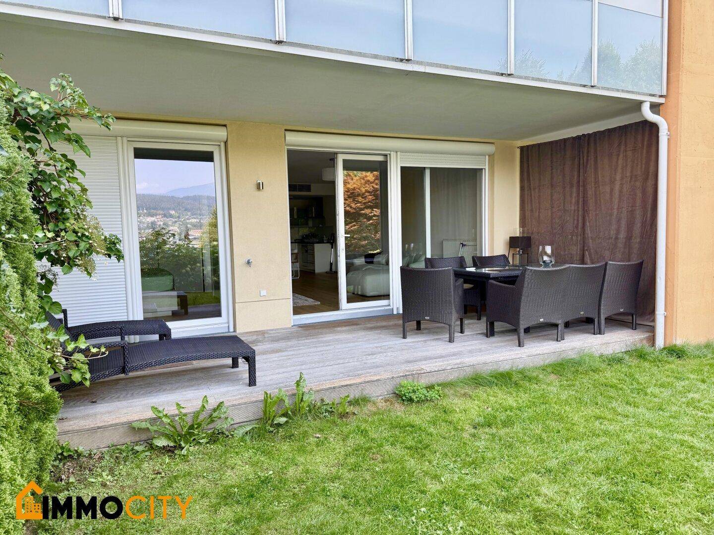 Geräumige Holzterrasse mit Gartenmöbeln und direktem Zugang zum gepflegten Rasenbereich.