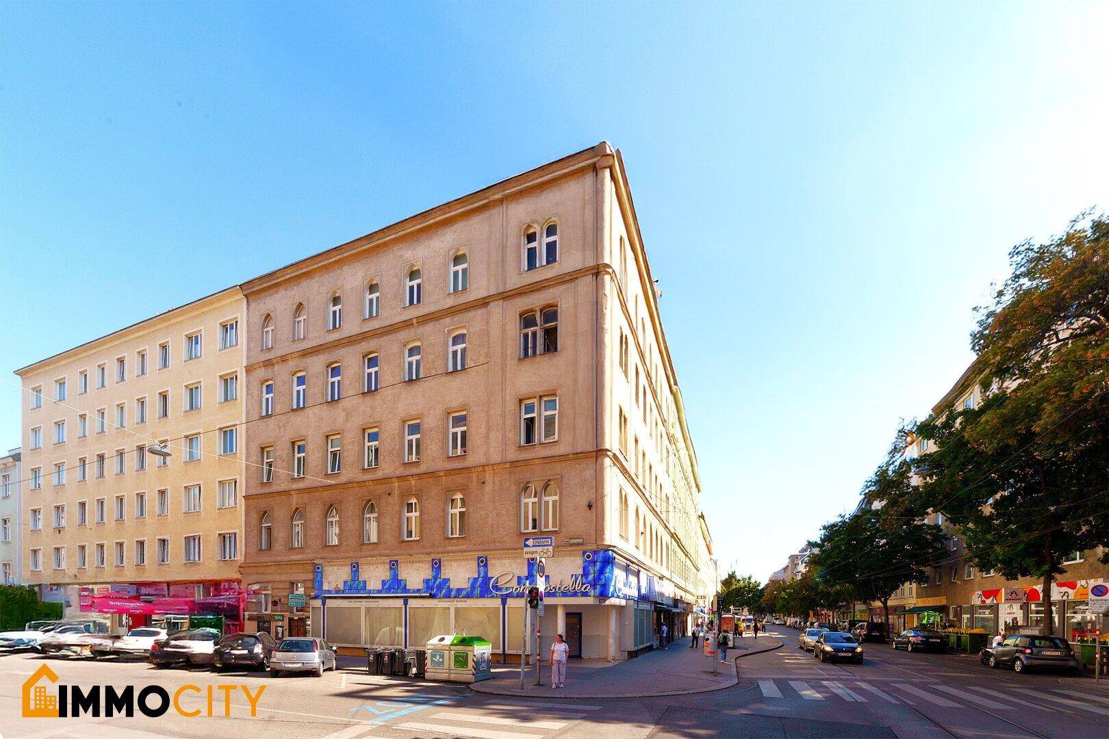 Historisches Eckgebäude in urbaner Umgebung mit Geschäften im Erdgeschoss und viel Tageslicht.