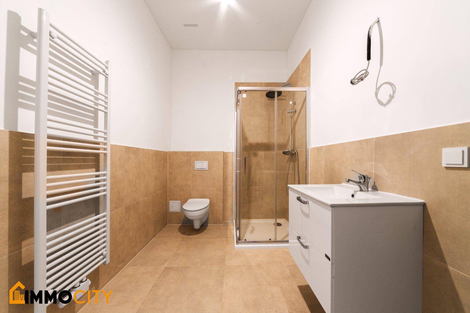 Modernes Badezimmer mit Dusche, WC, Waschtisch und beheiztem Handtuchhalter.