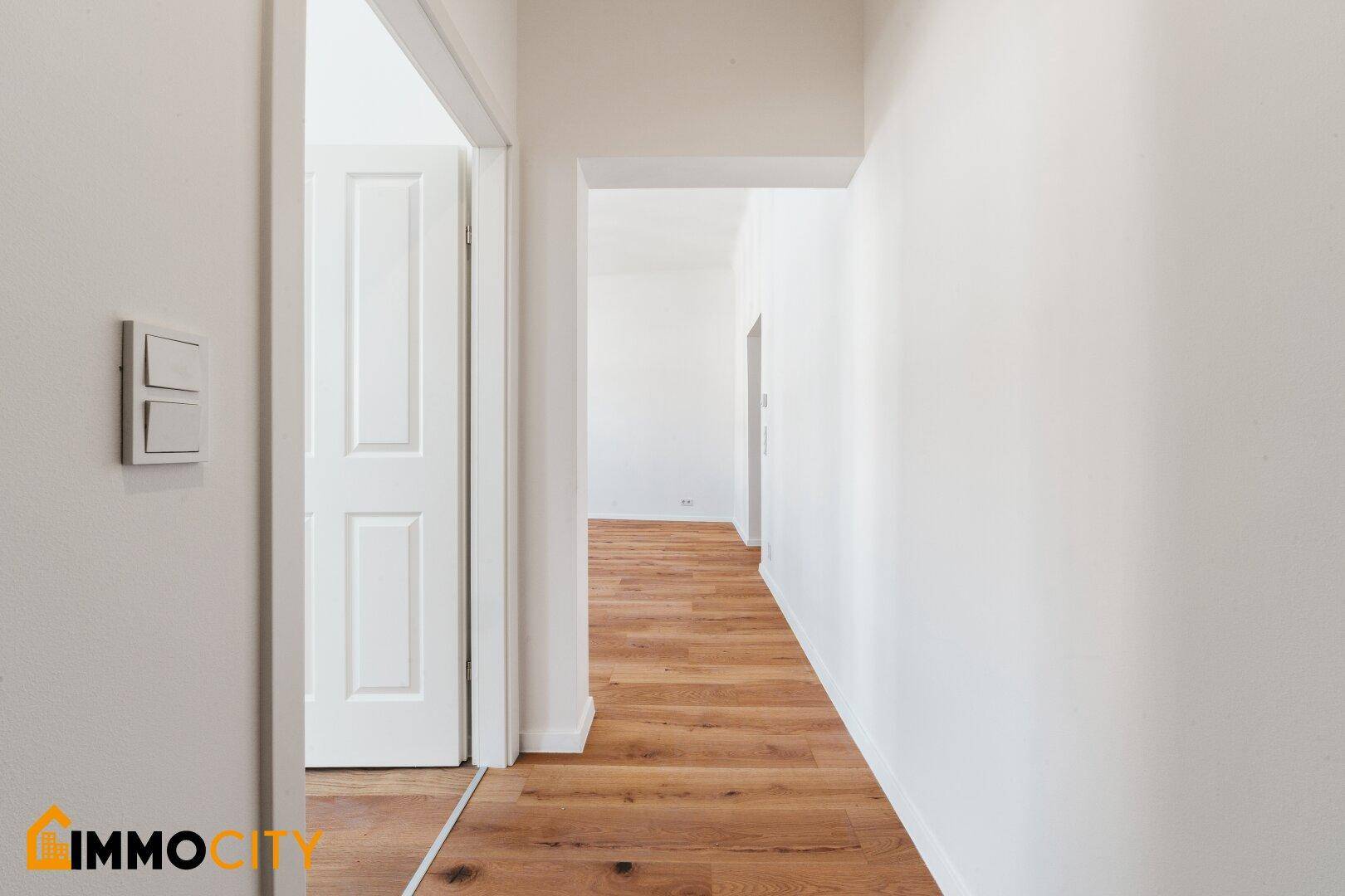 Langer, heller Flur mit Holzboden und Zugang zu den verschiedenen Zimmern der Wohnung.