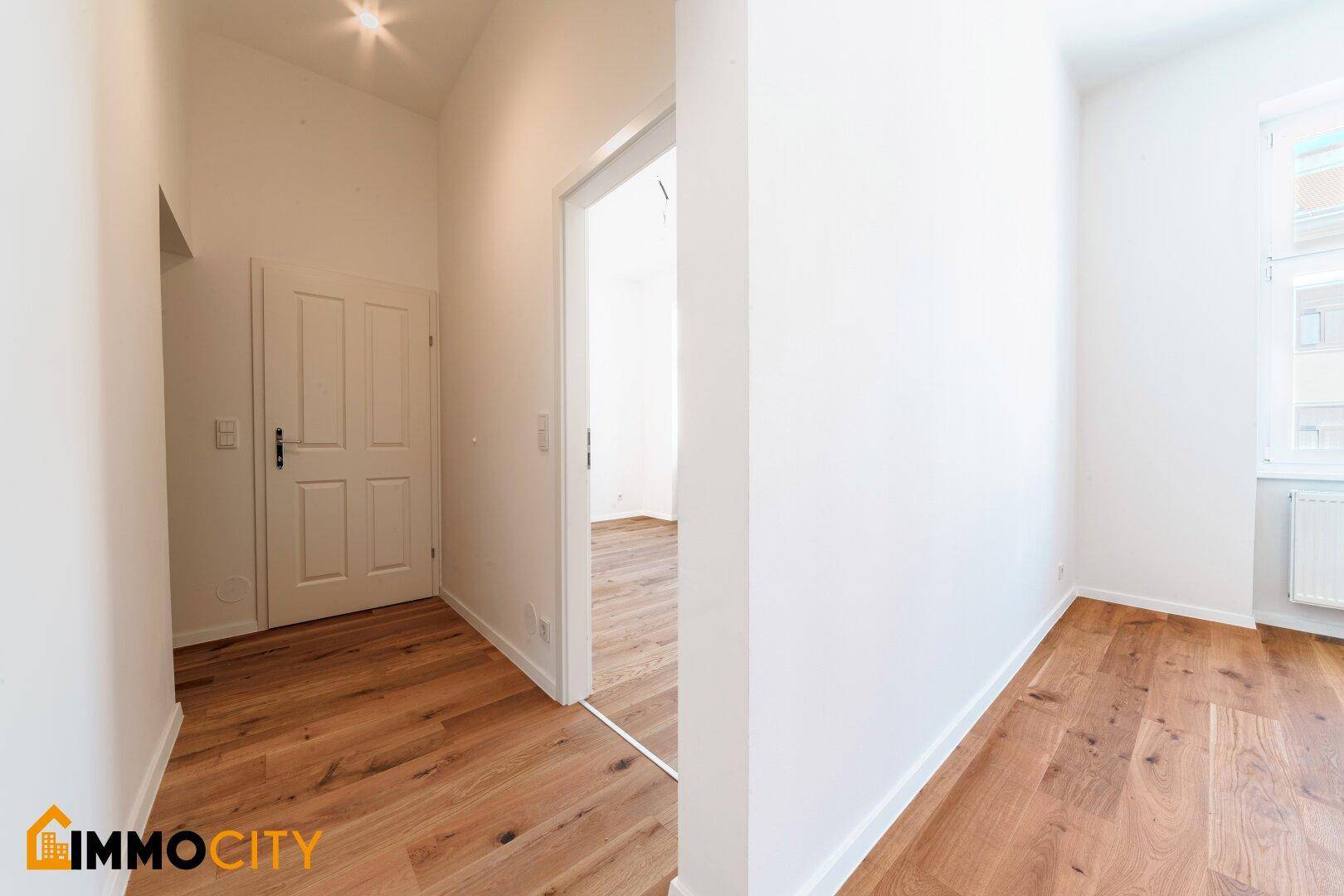 Heller Eingangsbereich mit Holzboden und Zugang zu den Wohnräumen der frisch renovierten Wohnung.