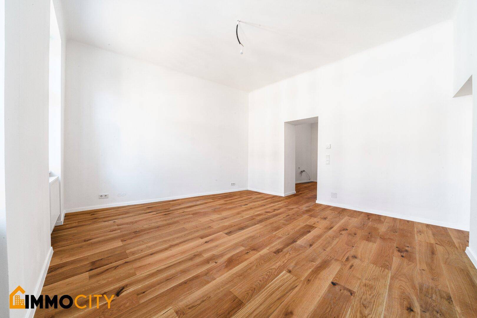 Großes, helles Zimmer mit Parkettboden und zwei Türöffnungen, vielseitig nutzbar.