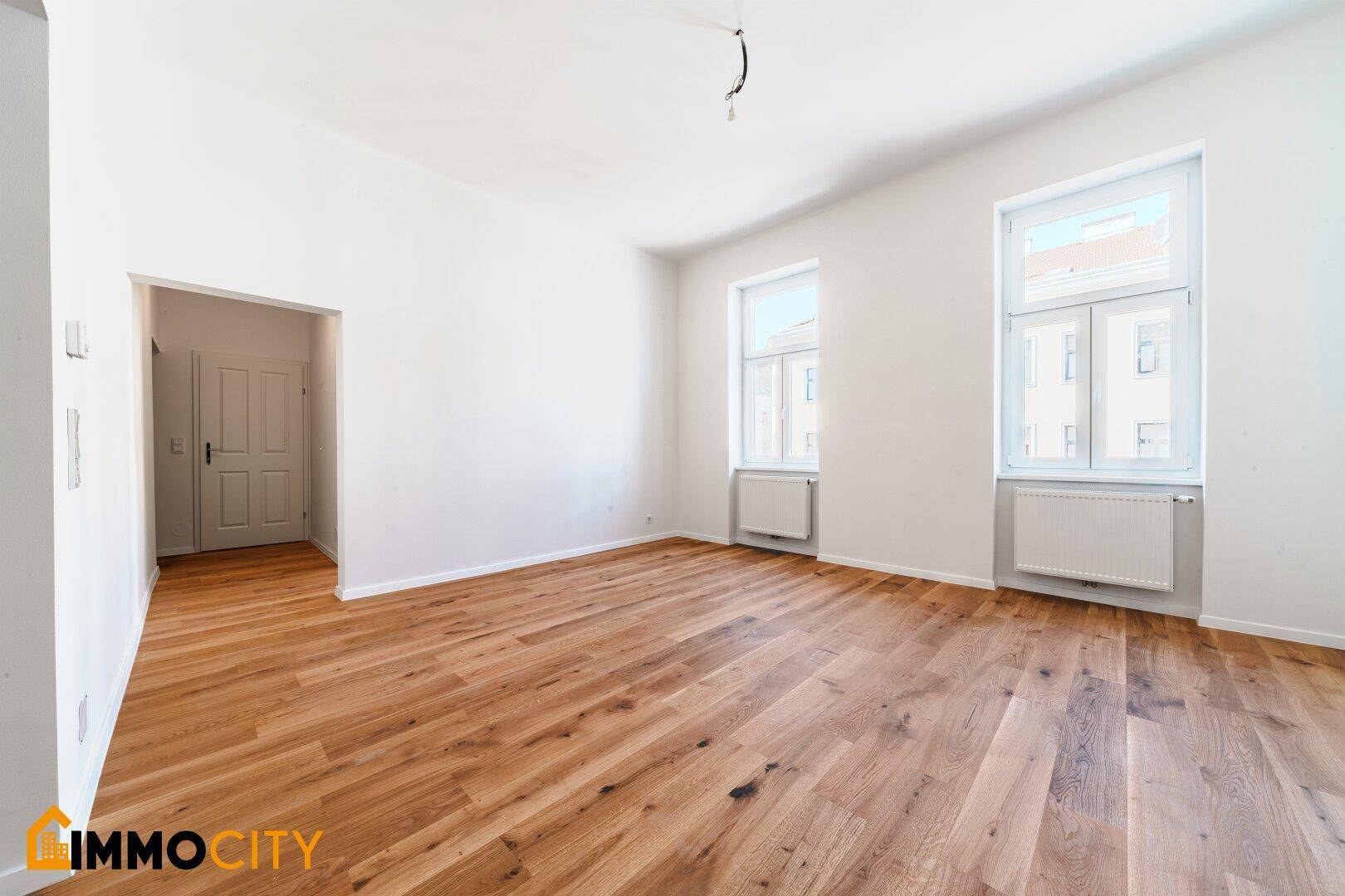 Helles Zimmer mit neuem Parkettboden und zwei Fenstern, frisch renoviert.
