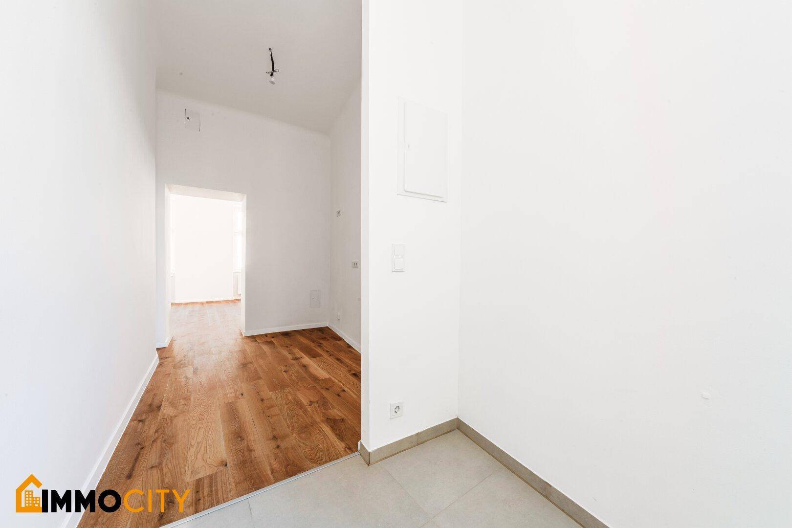 Heller Eingangsbereich mit Fliesenboden und Übergang zu Holzboden, frisch renoviert.