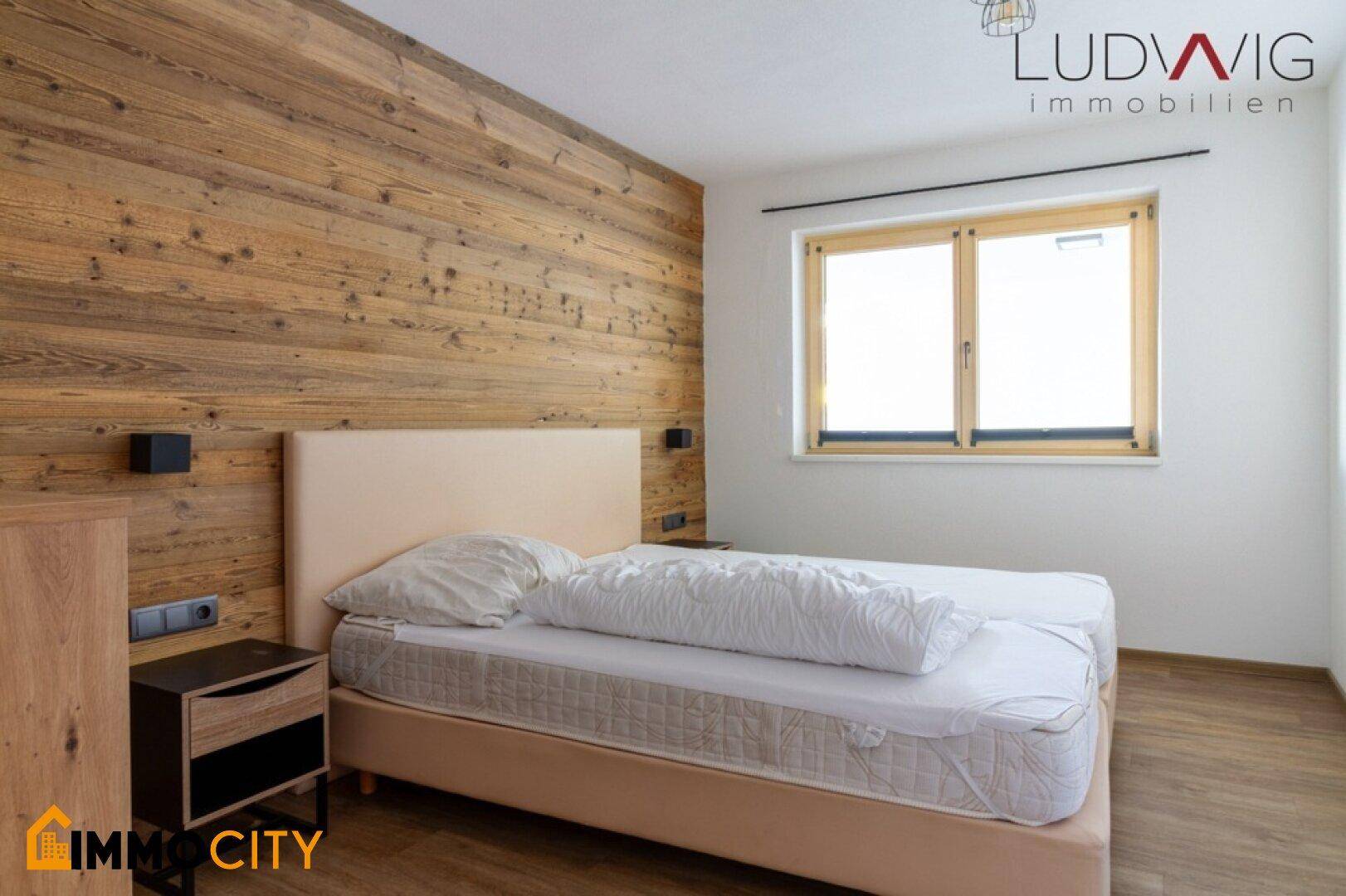 Gemütliches Schlafzimmer mit Holzwandverkleidung, Einzelbett und Fenster für natürliches Licht.
