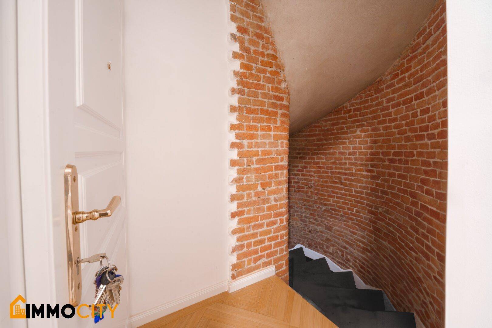 Historisches Treppenhaus mit freiliegenden Ziegelwänden, das in den Keller führt.