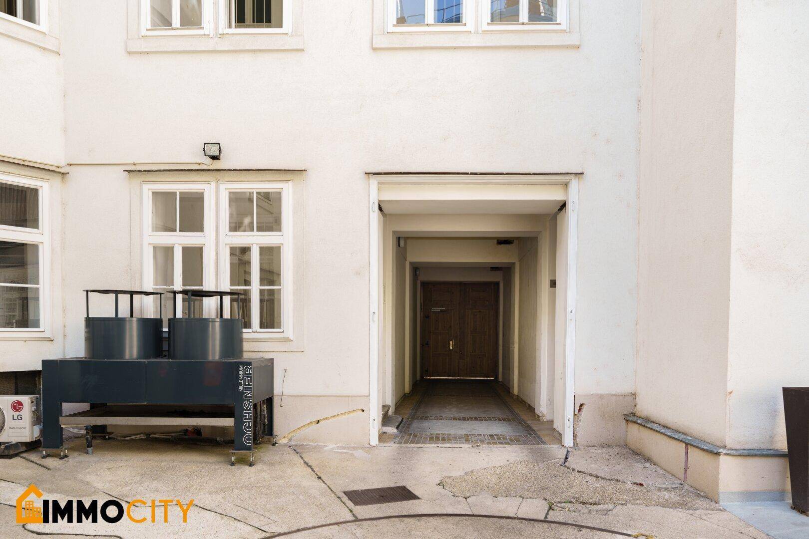 Historisches Gebäude an einer ruhigen Straße mit parkenden Autos und Bäumen.