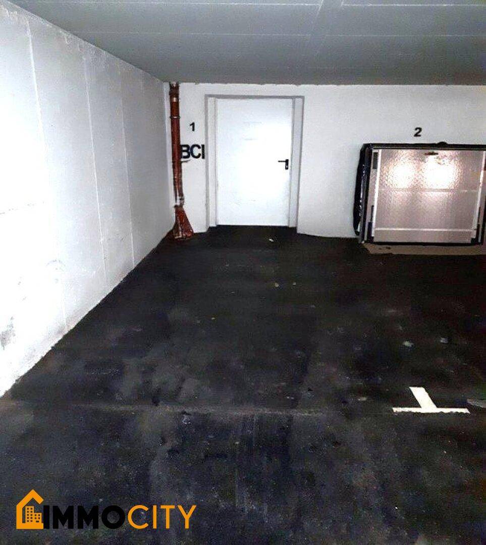 Leerer Garagenstellplatz in einer Tiefgarage mit weiß gestrichenen Wänden und Betonboden.