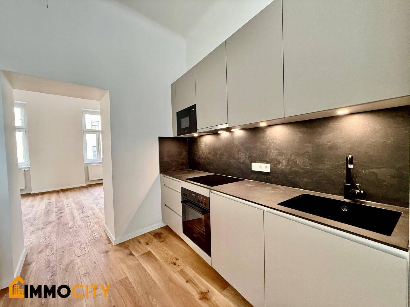 Helle, moderne Küche mit integrierten Siemens-Geräten und Blick in den angrenzenden Raum.