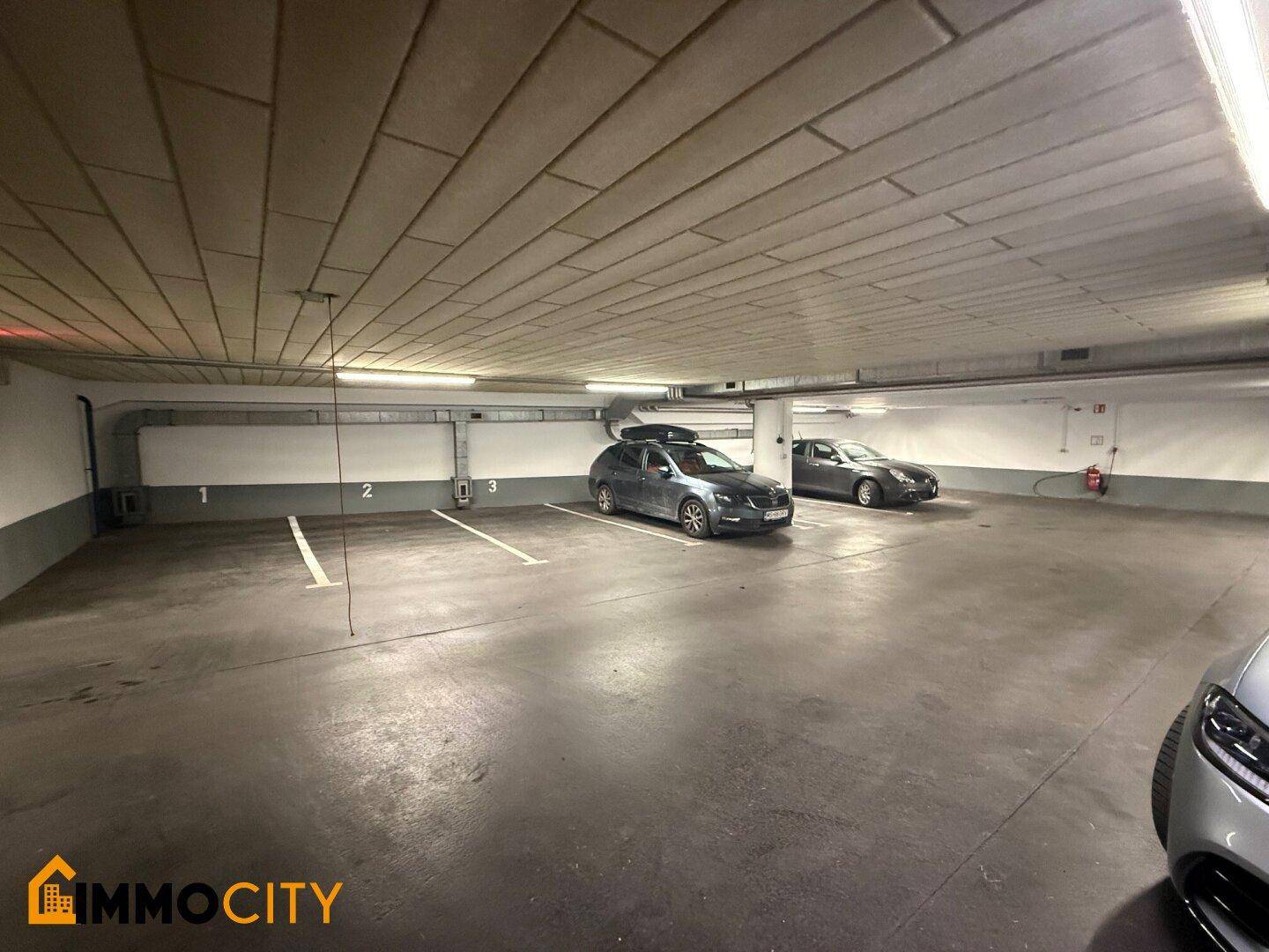 Geräumige Tiefgarage mit mehreren freien und belegten Stellplätzen und guter Beleuchtung.