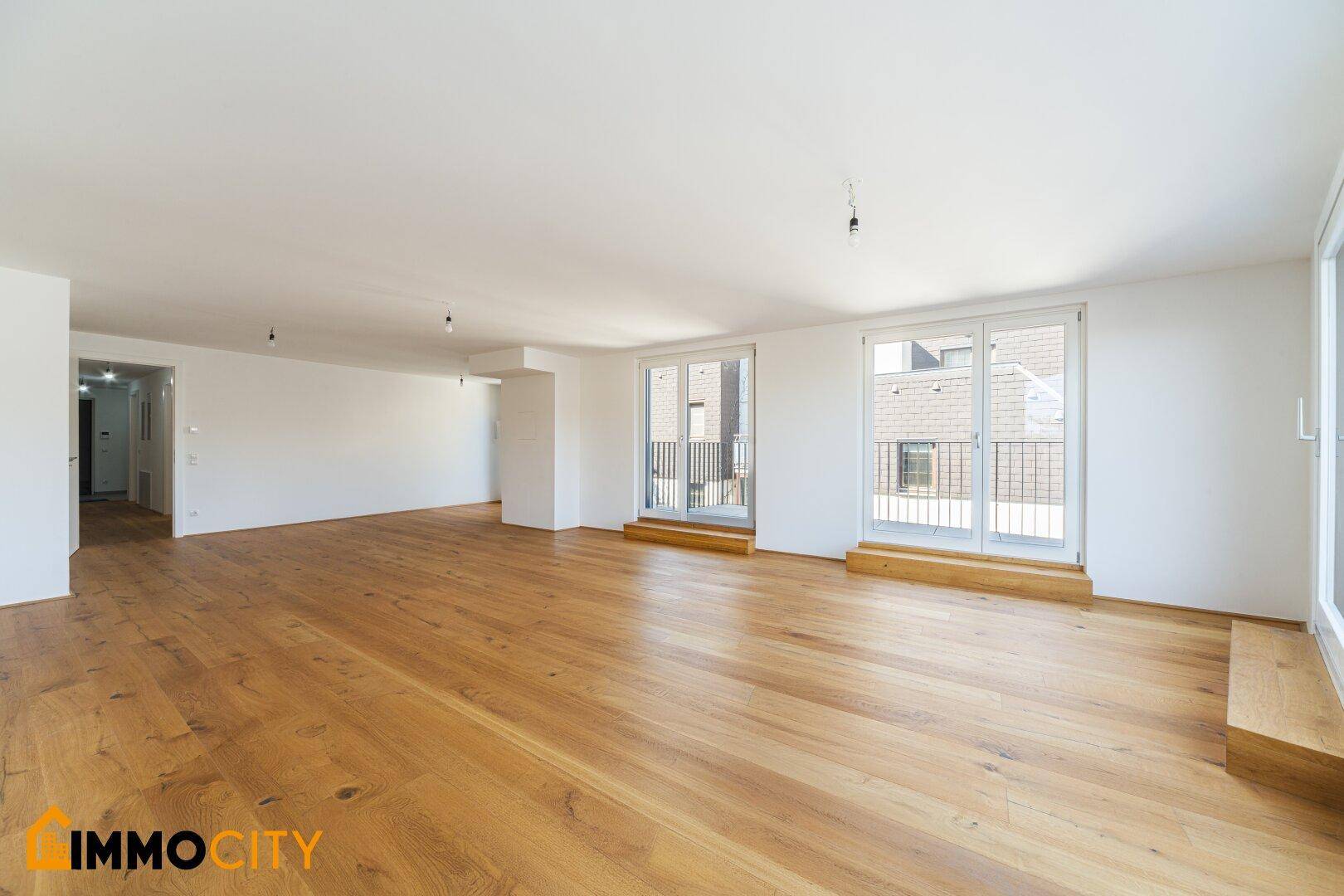 Heller Wohnraum mit hochwertigem Holzboden und Zugang zu einem französischen Balkon.