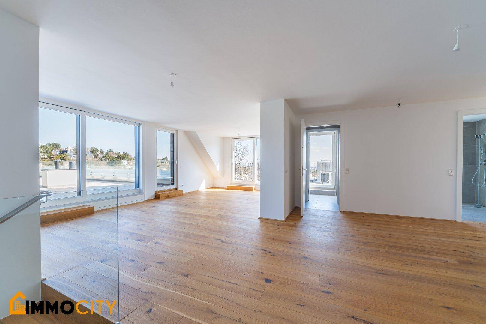 Geräumiger, heller Wohnraum mit Parkettboden und Blick auf die Umgebung sowie Zugang zur Terrasse.