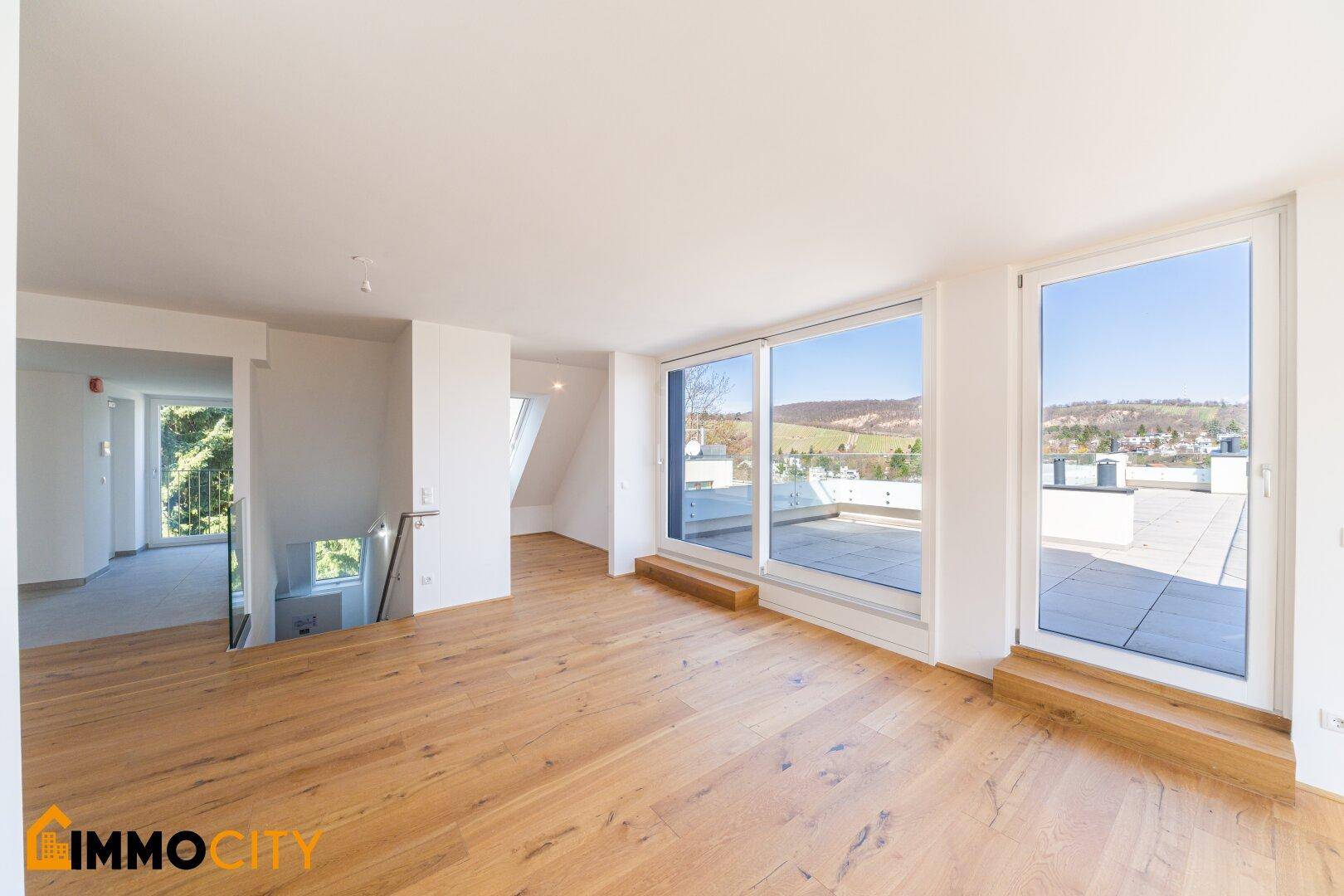 Geräumiger Wohnbereich mit Holzboden, großen Fenstern und direktem Zugang zu einer weitläufigen Dachterrasse.