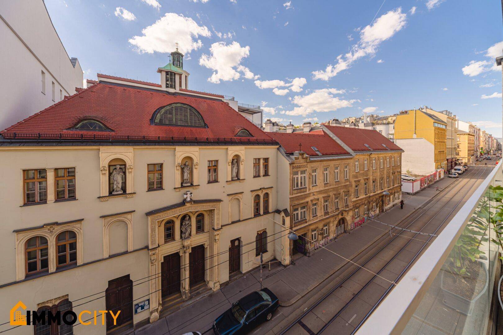 Blick von einem Balkon auf eine belebte Straße mit historischen Gebäuden.