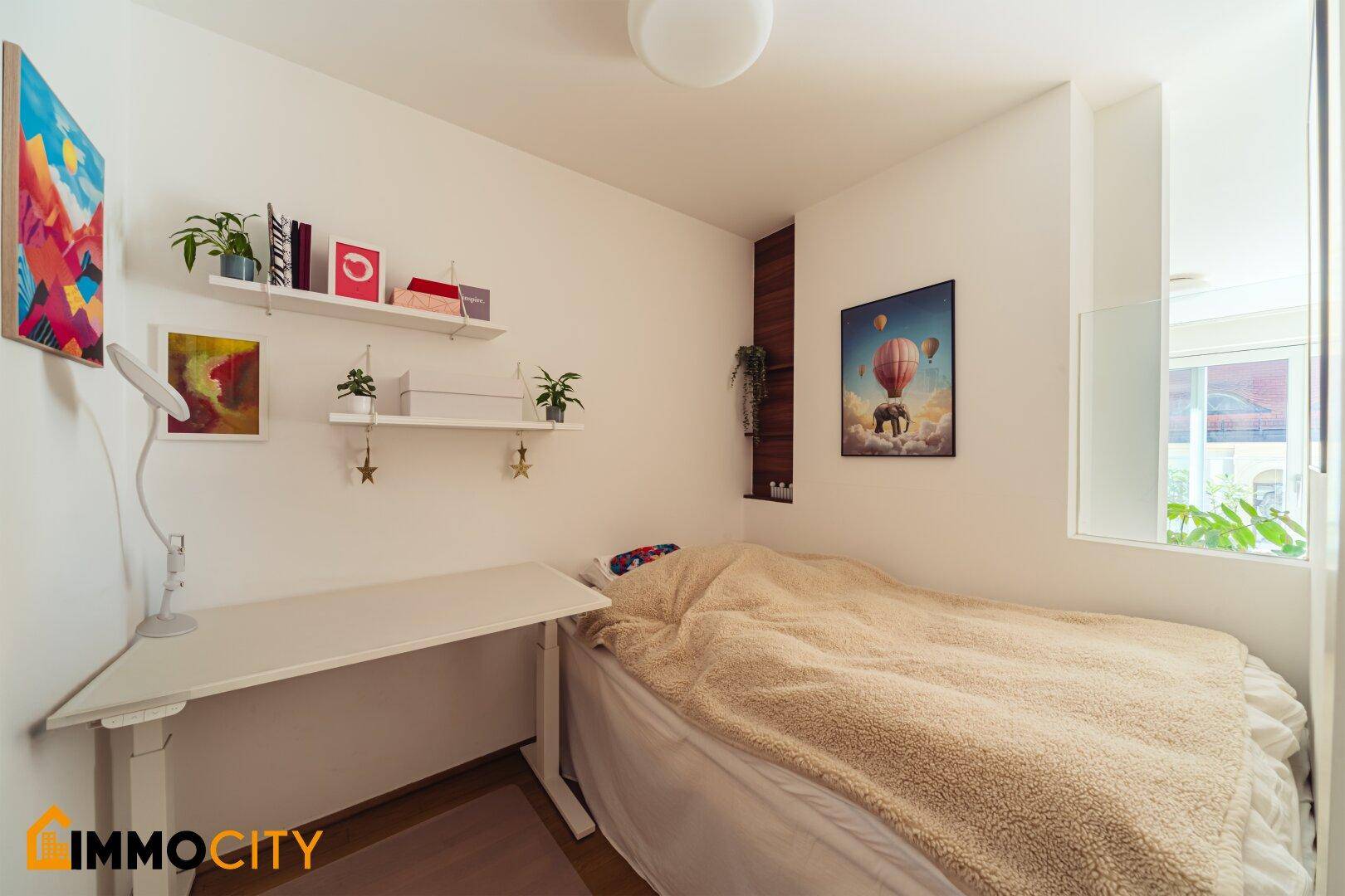 Kleines Schlafzimmer mit Bett, Schreibtisch und minimalistischer Dekoration.
