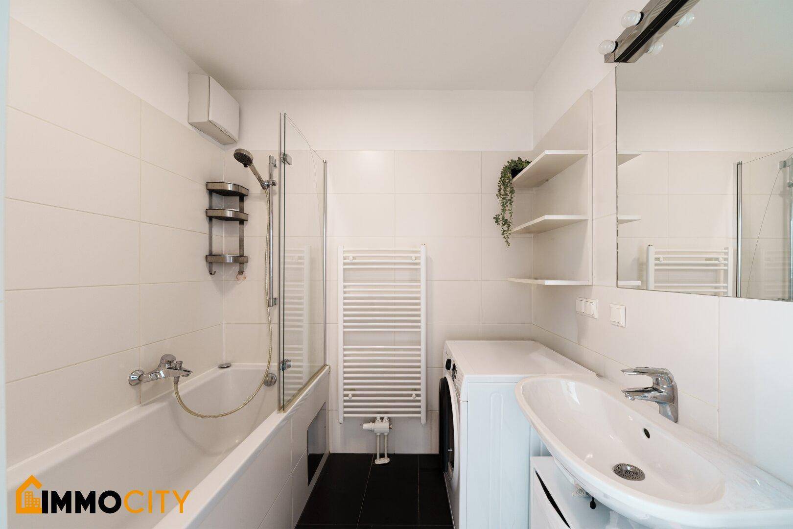 Modernes Badezimmer mit Badewanne, Dusche, Waschbecken und beheiztem Handtuchhalter.