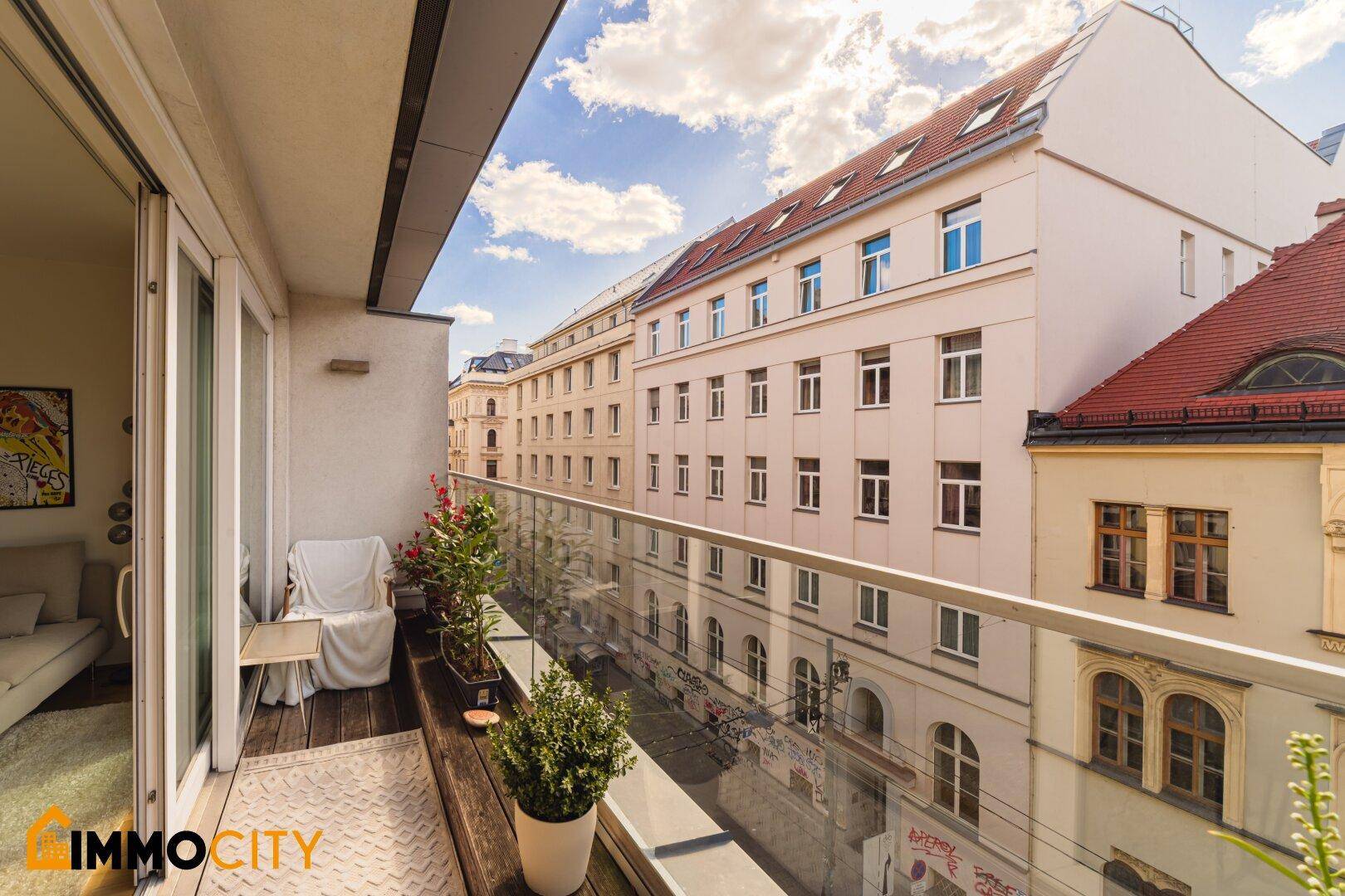 Schmaler Balkon mit Glasgeländer und Blick auf die umliegenden Gebäude.