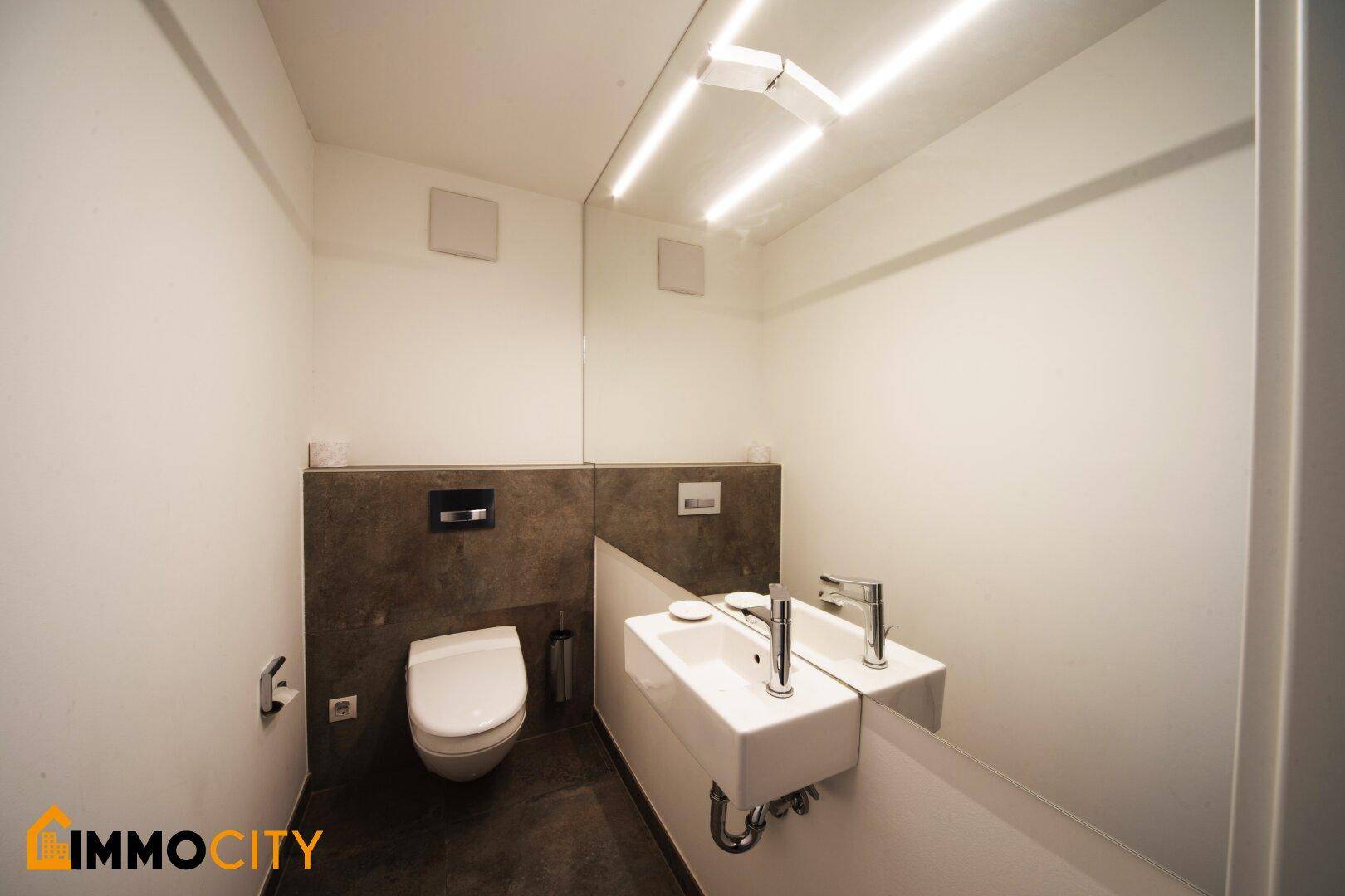 Modernes Gäste-WC mit kleinem Waschbecken, wandhängendem WC und minimalistischem Design.