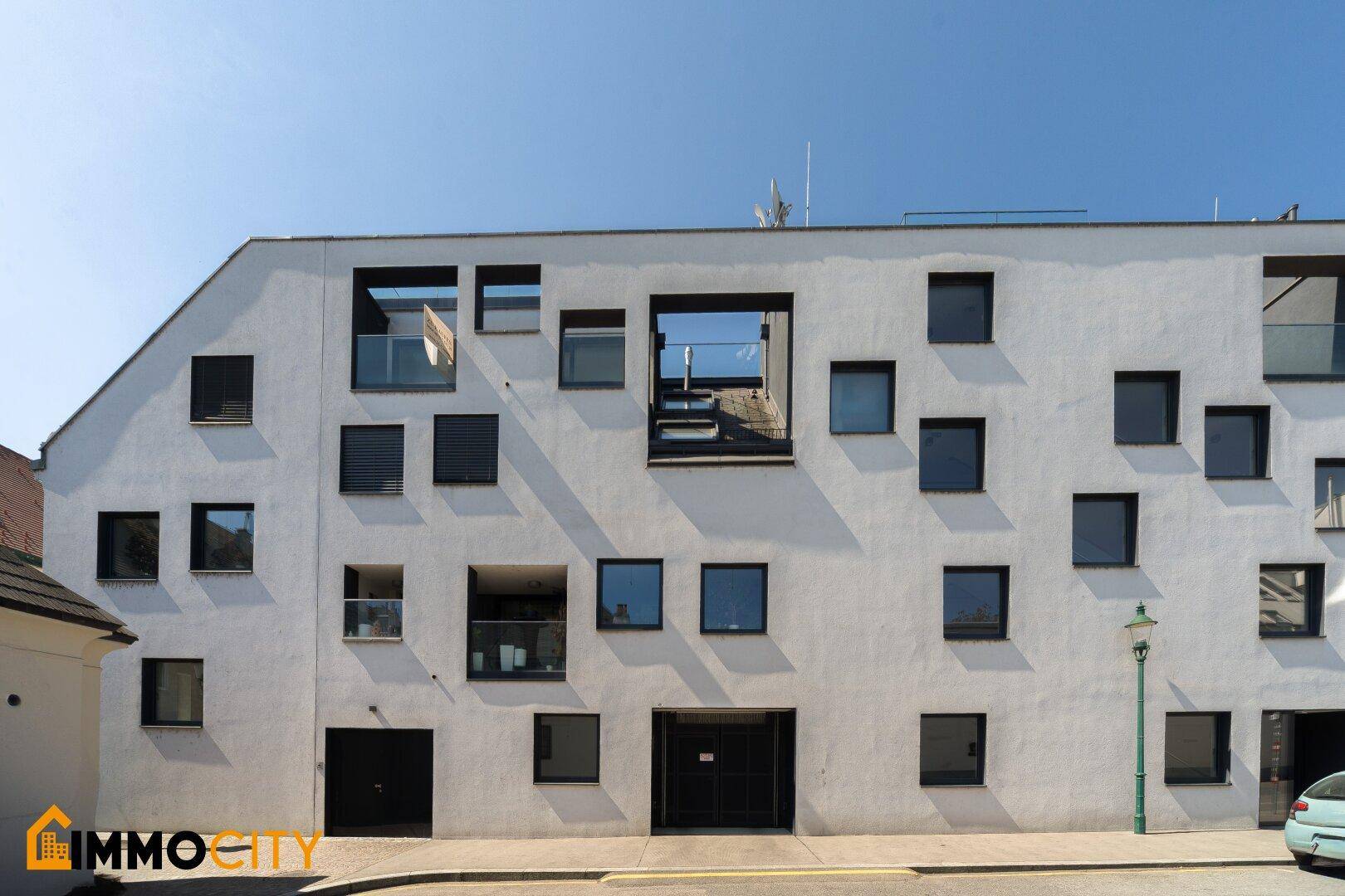 Weitläufige moderne Gebäudefassade mit vielen Fenstern und Balkonen in einer städtischen Umgebung.