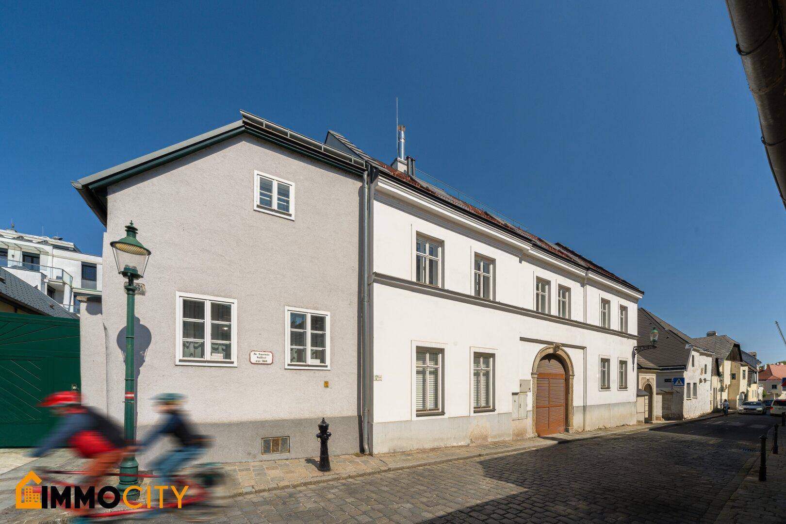 Historisches Gebäude mit traditioneller Architektur und Kopfsteinpflasterstraße im Vordergrund.