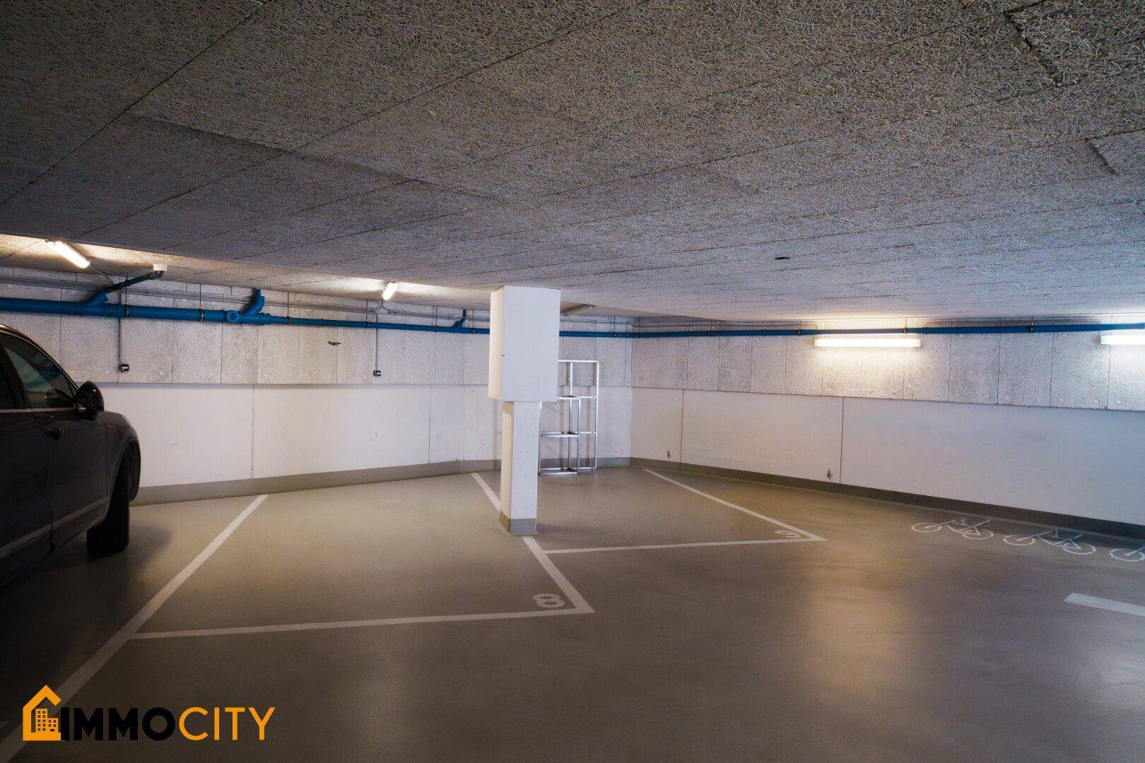 Tiefgarage mit einzelnen Parkplätzen und Fahrradstellflächen an der Wand.