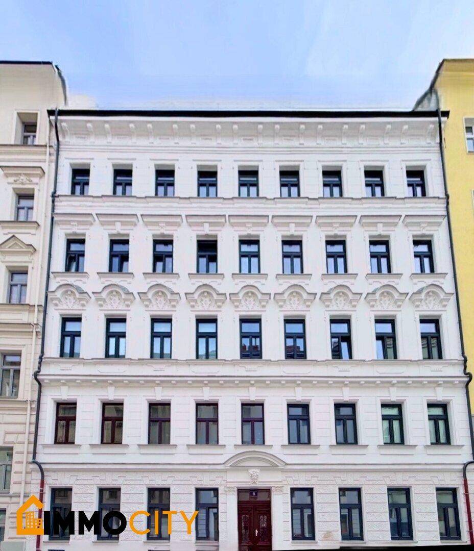 Historische Fassade eines Mehrfamilienhauses mit vielen Fenstern und klassischer Architektur.