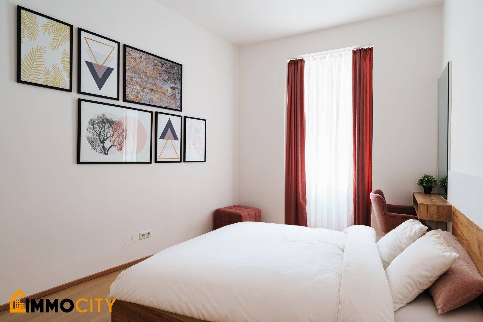 Gemütliches Schlafzimmer mit Holzbett, Parkettboden und dekorativen Bildern an der Wand.