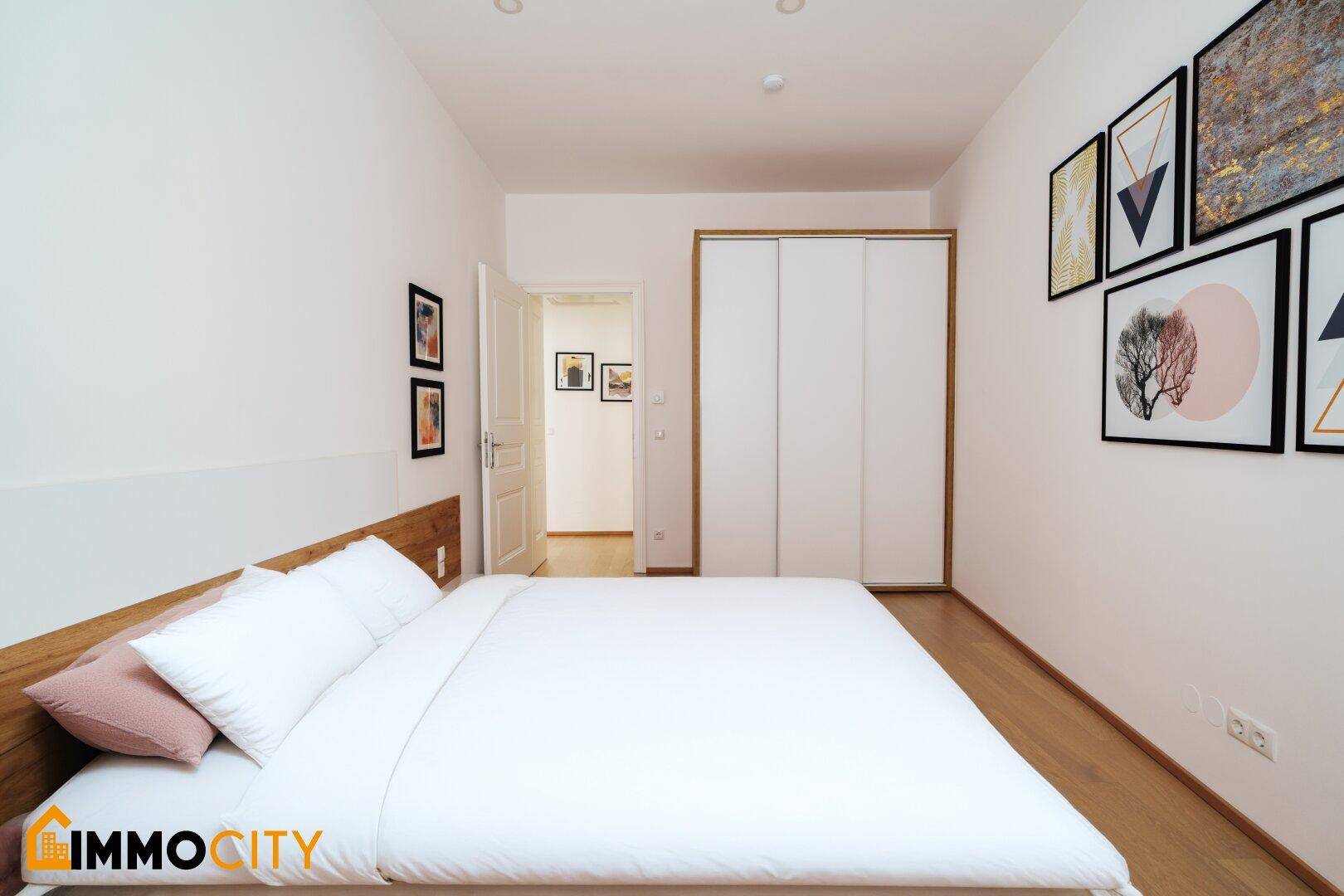 Schlafzimmer mit großem Bett, Einbauschrank und Zugang zu einem weiteren Raum.