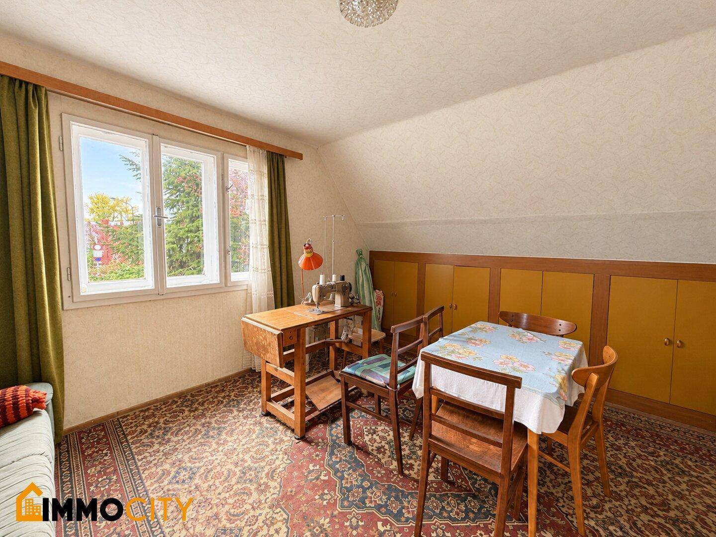 Dachzimmer mit Schreibtisch, Nähmaschine und Stauraum unter der Dachschräge.