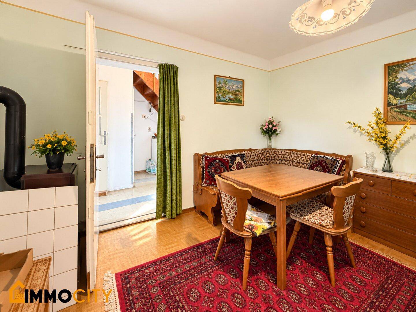 Rustikaler Essbereich mit Holztisch, Sitzbank und einem traditionellen Kachelofen.