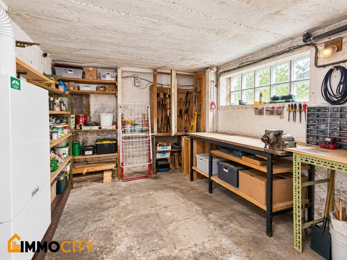 Gut ausgestattete Werkstatt im Keller mit Arbeitsflächen, Regalen und Werkzeugen.