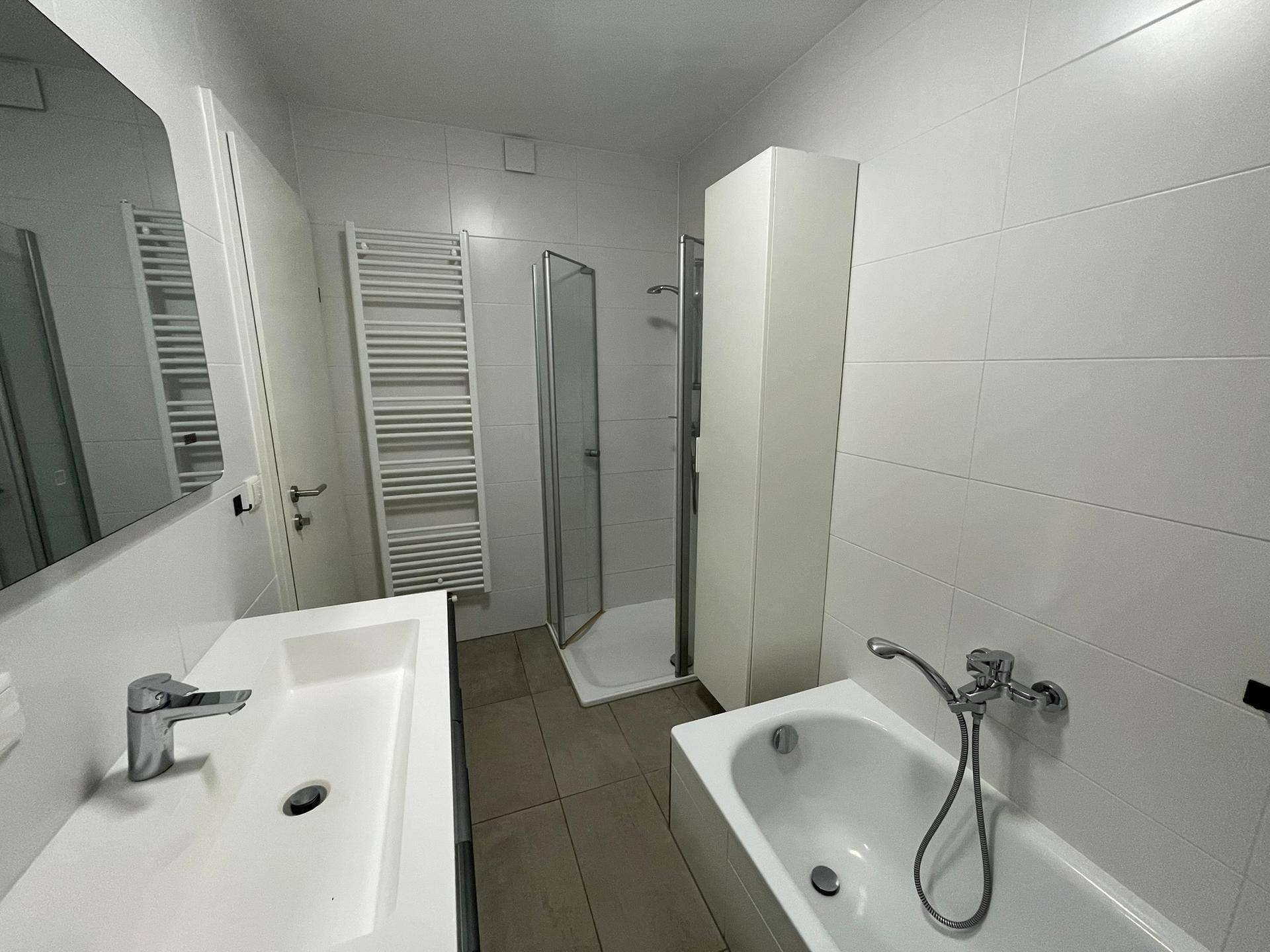 Modernes Badezimmer mit Badewanne, separater Dusche, Einzelwaschbecken und Handtuchheizkörper.