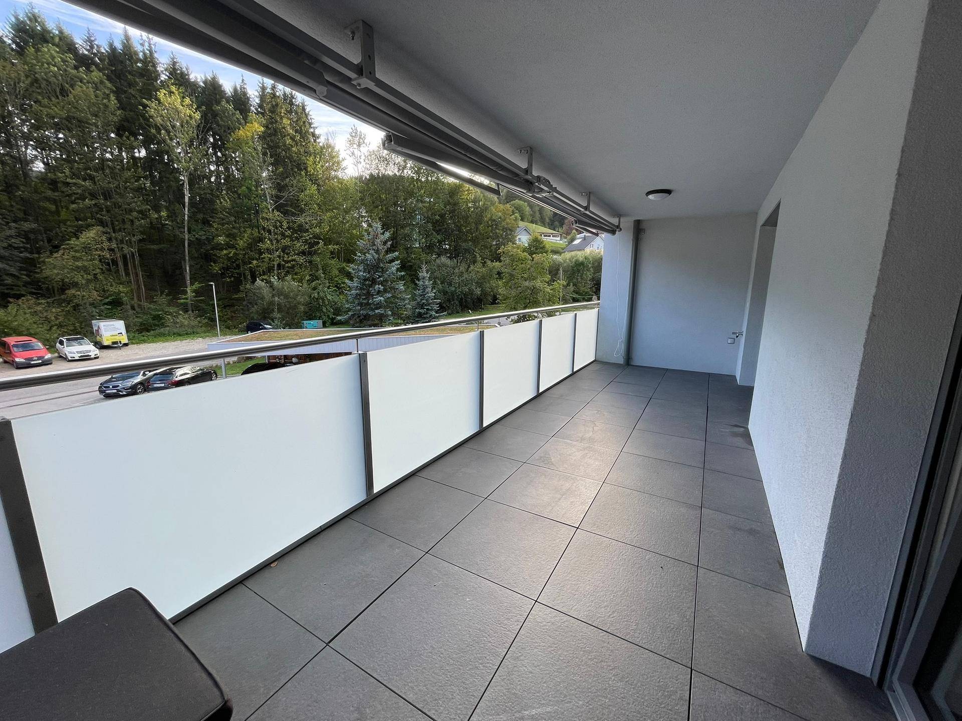 Geräumiger Balkon mit Fliesenboden und Blick auf die umliegende Natur.